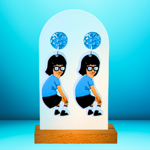Load image into Gallery viewer, Earrings against a bright blue backdrop featuring Tina Belcher from Bob’s Burgers dancing