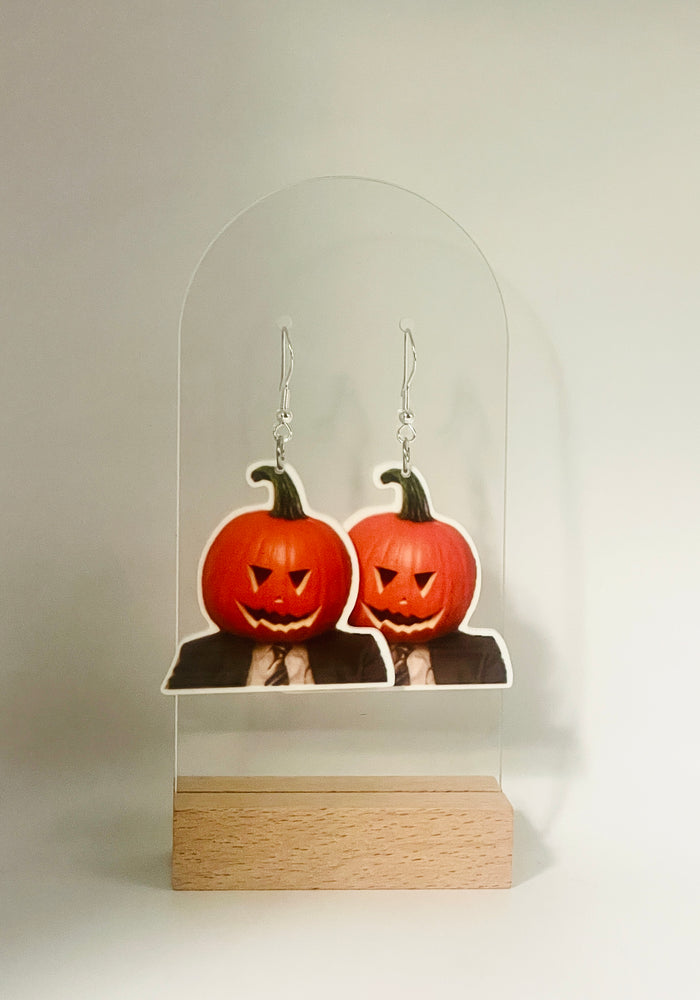 Earrings featuring Dwight Schrute from “The Office” with a pumpkin stuck on his head, symbolizing his love for practical jokes and farm-related humor during the spooky season.