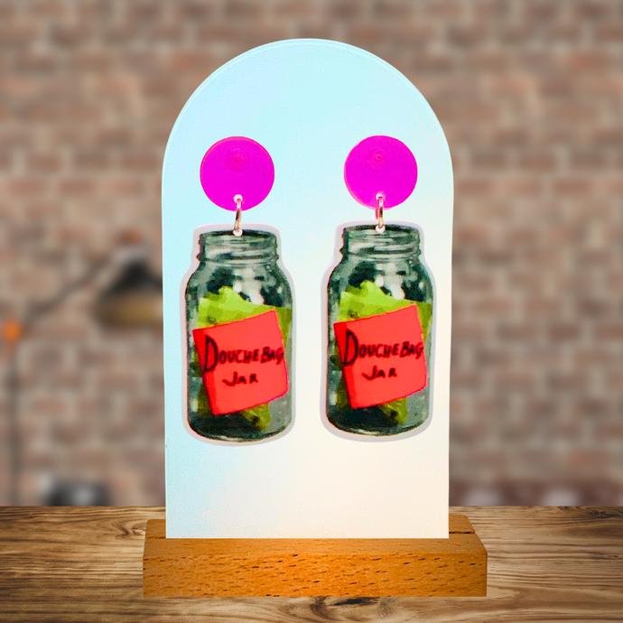 Earrings with neon pink studs and a dangling “Douchebag Jar” earring from New Girl