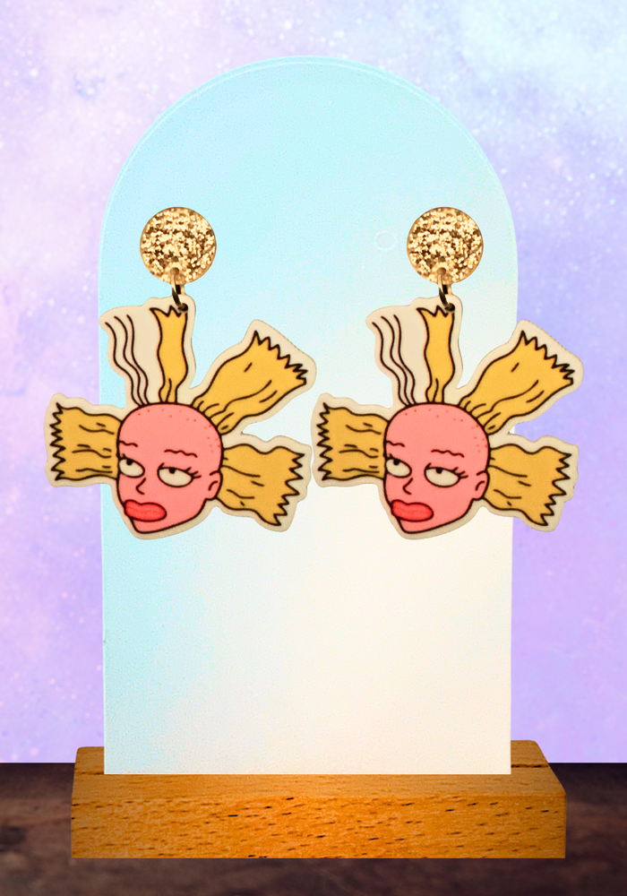 An earring stand with Cynthia doll head earrings from Rugrats on a purple background