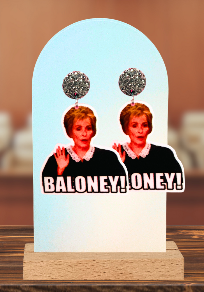 Judge Judy earrings on an earring stand featuring the judge saying “Baloney!”