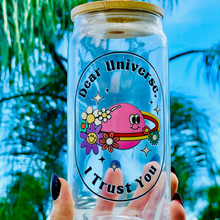 Load image into Gallery viewer, A 16oz BPA-free glass cup with a UVDTF design featuring a pink planet with flowers, sparkles, and the phrase "Dear Universe, I Trust You," complete with a bamboo lid and reusable glass straw.