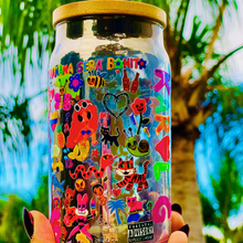 Load image into Gallery viewer, A 16 oz glass cup with a colorful Karol G-inspired UVDTF wrap featuring vibrant symbols, designs, and playful details. Includes a bamboo lid and reusable glass straw, perfect for cold drinks. BPA-free and handwash only.