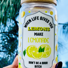 Load image into Gallery viewer, 16 oz BPA-free glass cup with a vibrant lemon design and cheeky quote: 'When life gives you lemons, make lemonade, don’t be a sour bitch.' Includes a bamboo lid and reusable glass straw.