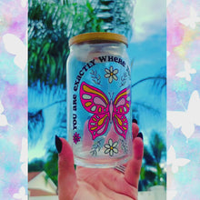 Load and play video in Gallery viewer, A 16 oz glass cup featuring a UVDTF wrap with a pink butterfly, daisies, and the phrase “You’re Exactly Where You Need To Be.” Comes with a bamboo lid and reusable glass straw. BPA-free and handwash only.