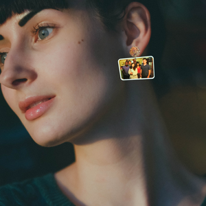 A model wearing earrings featuring a photo of the New Girl cast after being rescued from their cruise room