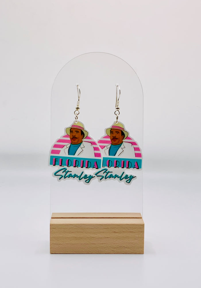 Earrings showcasing “Florida Stanley” from “The Office” in his white suit and fedora, set against a vintage Florida-themed background, embodying a relaxed and adventurous vibe