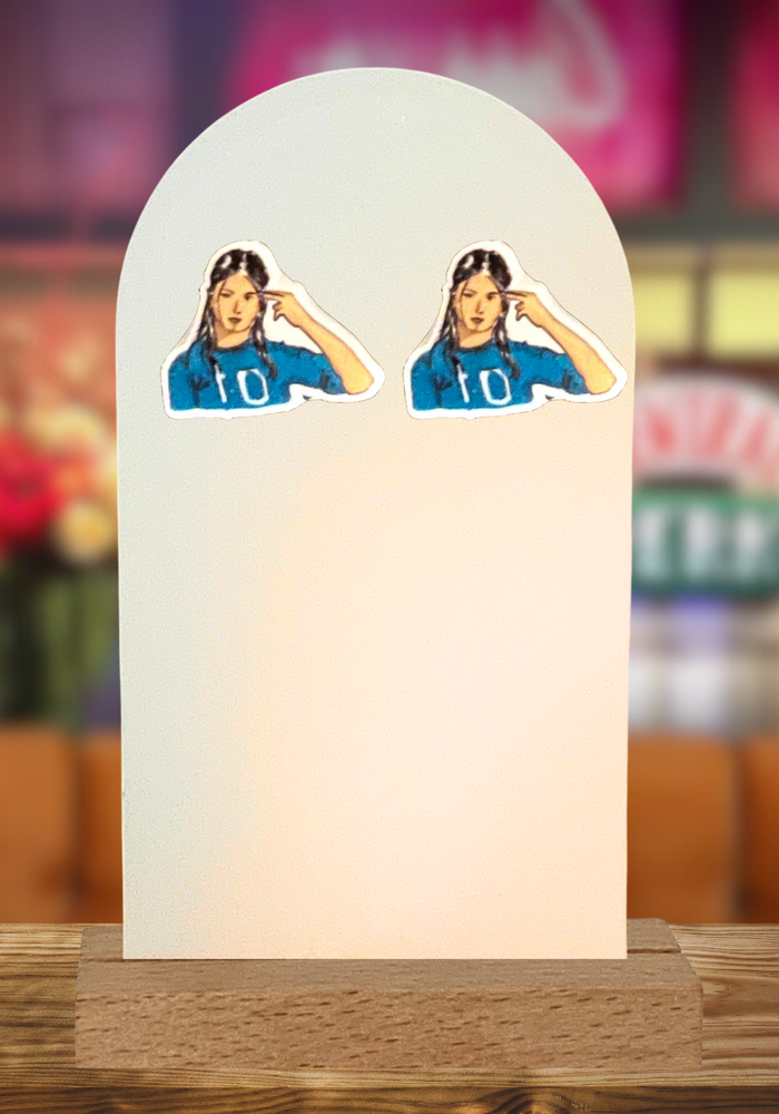 Stud earrings featuring Rachel Green from Friends doing the “Unagi” gesture. The background is the Central perk coffee house. 