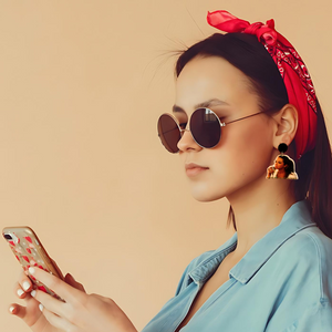 A model looking at her phone wearing Stassi Schroder earrings from Vanderpump Rules that say " I am the devil and don't you forget it"