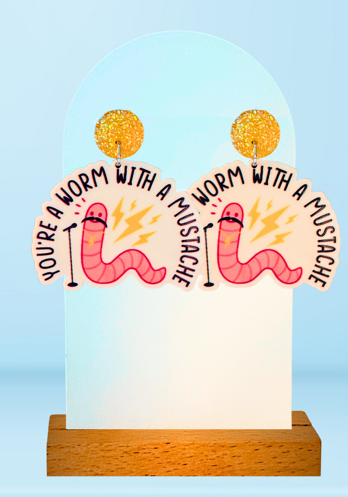 Blue background with earrings featuring a pink worm with a mustache talking into a mic with lightning bolts, referencing James Kennedy's diss to Tom Sandoval from Vanderpump Rules.