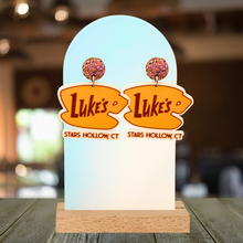 Load image into Gallery viewer, A cafe background with earrings displayed that feature the “Luke’s Diner” logo from Gilmore girls
