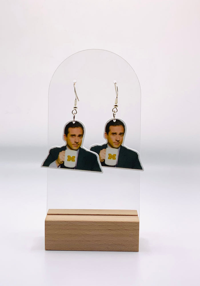  Earrings depicting Michael Scott from “The Office” holding his coffee mug with the University of Michigan logo, capturing his proud yet clueless smile in a design that blends TV fandom with collegiate spirit.