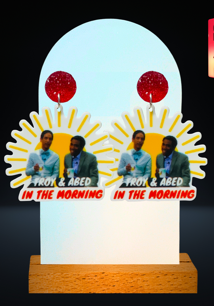 A black background with earrings featuring Troy and Abed from 