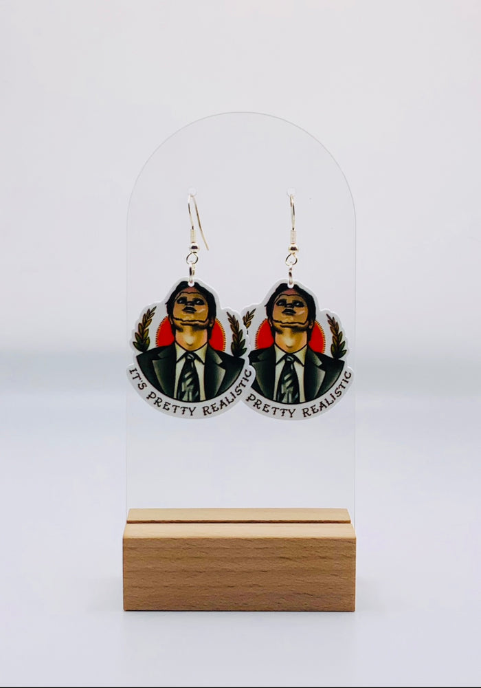 Earrings showcasing Dwight Schrute from 'The Office' eerily wearing the face of a CPR dummy, reminiscent of a scene from 'Silence of the Lambs.' The caption 'It's pretty realistic' is displayed underneath, capturing the bizarre and humorous moment in vivid detail