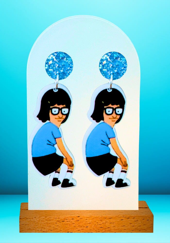 Earrings against a bright blue backdrop featuring Tina Belcher from Bob’s Burgers dancing