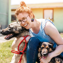 Load image into Gallery viewer, A woman posing with her dog wearing earrings featuring the invite from James and Raquel&#39;s Season 7 puppy shower for their dog Graham
