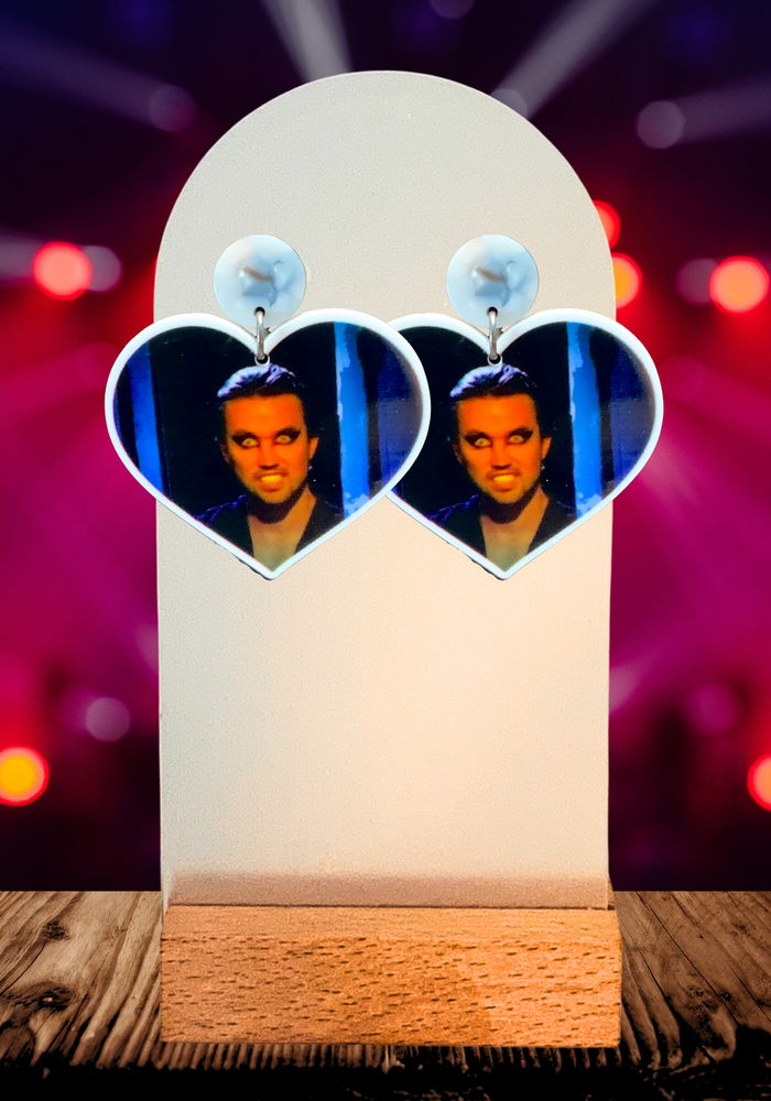 Stage background with heart shaped earrings at the forefront featuring a close up of Mac as the Nightman from Always Sunny in Philadelphia
