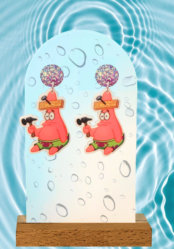 Display photo of Patrick Star from SpongeBob SquarePants sitting on the ground confused holding a hammer with a board nailed into his head. The earring display is submerged in water