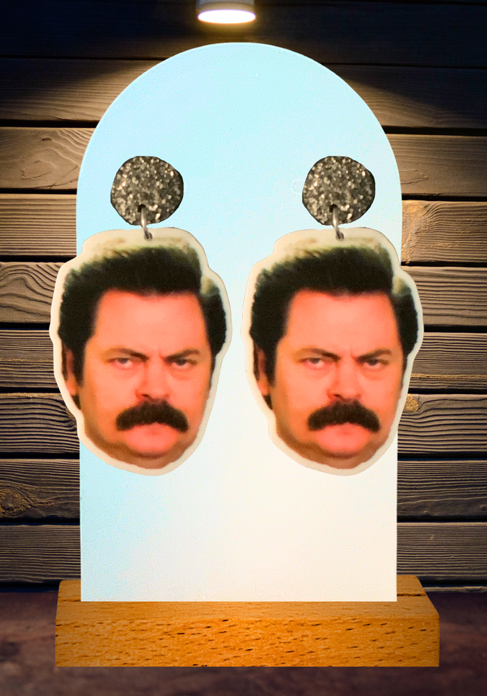 Close-up of Ron Swanson’s face on Parks and Rec inspired earrings, capturing the essence of his iconic, no-nonsense expression for fans to wear with pride.