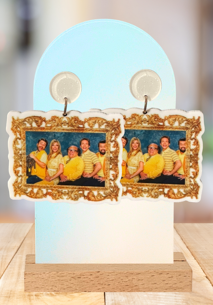 Earrings on an arched stand featuring a framed photo of the Always Sunny in Philadelphia cast