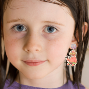 Little girl smiling into the camera modeling Patrick Star earrings