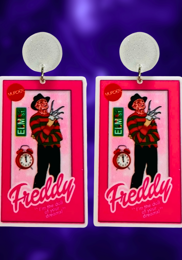 Earrings featuring Freddy Krueger in a Barbie-style box, with an Elm Street sign and alarm clock, ideal for fans of horror movies and playful Halloween fashion.