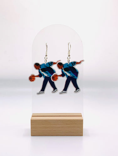 Earrings featuring an illustration of Stanley Hudson from 'The Office' in a side profile, playing basketball. The design captures Stanley's focused expression and his casual basketball attire, as seen in the memorable scene where the Dunder Mifflin staff plays a game. 