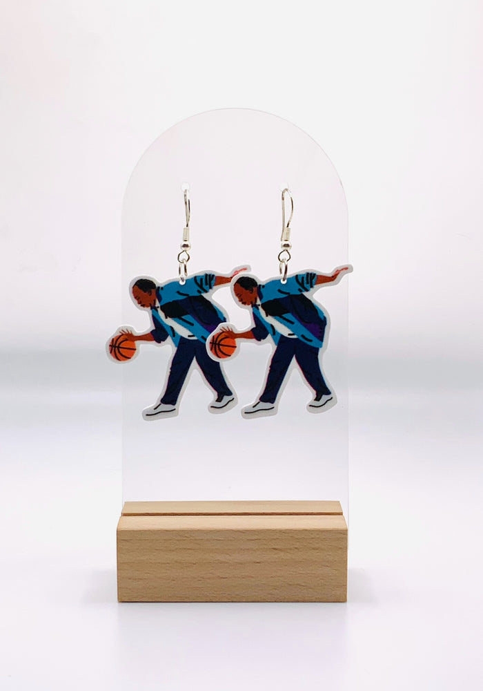 Earrings featuring an illustration of Stanley Hudson from 'The Office' in a side profile, playing basketball. The design captures Stanley's focused expression and his casual basketball attire, as seen in the memorable scene where the Dunder Mifflin staff plays a game. 