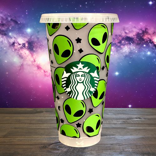 A 16 oz BPA-free Starbucks-compatible reusable cold cup with a vinyl wrap featuring bright green aliens and stars. Includes a clear lid and reusable straw, perfect for iced coffee lovers and fans of extraterrestrial designs.