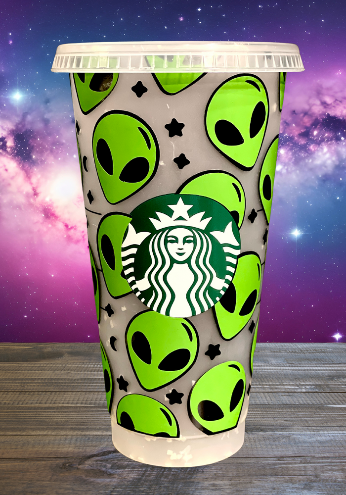 A 16 oz BPA-free Starbucks-compatible reusable cold cup with a vinyl wrap featuring bright green aliens and stars. Includes a clear lid and reusable straw, perfect for iced coffee lovers and fans of extraterrestrial designs.