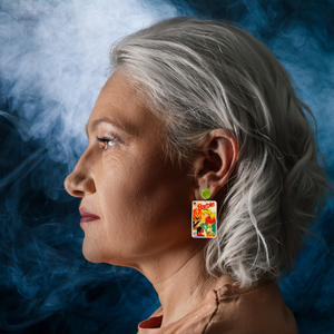 A model in front of a smoky background wearing earrings that feature a vintage Halloween Barbie comic cover from 1993, showing Barbie handing out candy to trick-or-treaters, perfect for fans of Barbie and nostalgic Halloween accessories