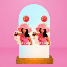 Load image into Gallery viewer, Pink background with earrings featuring Lisa Vanderpump in a pink dress and derby hat, holding a glass of rosé with the caption &quot;I don&#39;t care&quot; from Vanderpump Rules.
