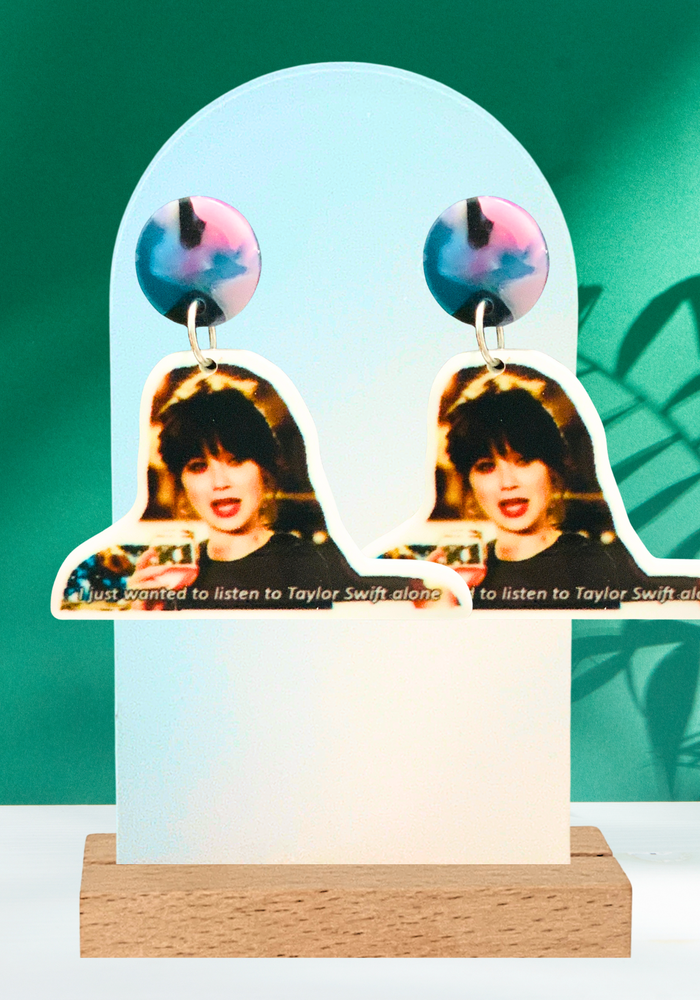  A green backdrop featuring New Girl earrings with Jess crying with the caption “I just wanted to listen to Taylor Swift alone”