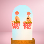 Close-up image of “Slut Pig” earrings, inspired by the iconic Real Housewives of Beverly Hills moment between Kim Richards and Brandi Glanville, perfect for Bravo reality TV fans.