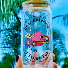 Load image into Gallery viewer, A 16oz BPA-free glass cup with a UVDTF design featuring a pink planet with flowers, sparkles, and the phrase &quot;Dear Universe, I Trust You,&quot; complete with a bamboo lid and reusable glass straw.
