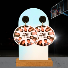 Load image into Gallery viewer, Illustrated ‘One Tree Hill’ cast earrings featured on an earring stand in front of a basketball court
