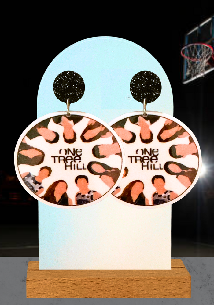Illustrated ‘One Tree Hill’ cast earrings featured on an earring stand in front of a basketball court