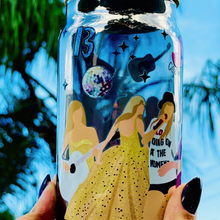 Load image into Gallery viewer, BPA-free 20 oz glass cup featuring Taylor Swift&#39;s iconic eras tour outfits in a vibrant UVDTF wrap design, complete with a bamboo lid and glass straw.
