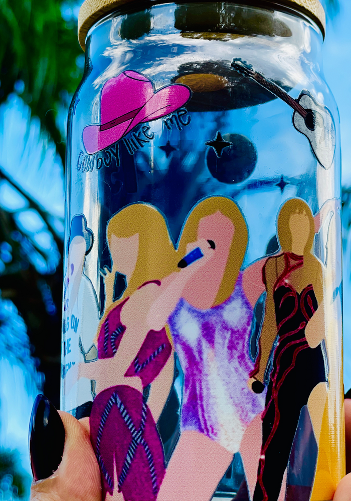 BPA-free 20 oz glass cup featuring Taylor Swift's iconic eras tour outfits in a vibrant UVDTF wrap design, complete with a bamboo lid and glass straw.