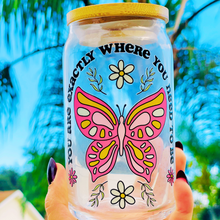 Load image into Gallery viewer, A 16 oz glass cup featuring a UVDTF wrap with a pink butterfly, daisies, and the phrase “You’re Exactly Where You Need To Be.” Comes with a bamboo lid and reusable glass straw. BPA-free and handwash only.
