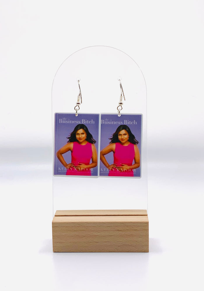 Earrings inspired by Kelly Kapoor's iconic 'Business Bitch' moment from The Office. A fictional purple book cover featuring a photo of Kelly with the title 