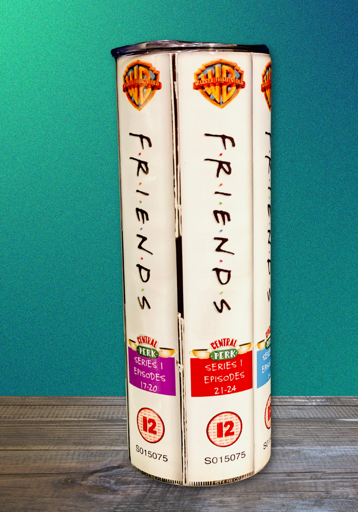 A 20 oz stainless steel insulated tumbler featuring a sublimated design inspired by the TV show Friends, showcasing Series 1 episodes like Episodes 17-20 and Episodes 21-24. Includes a secure lid and reusable metal straw, perfect for hot and cold drinks.