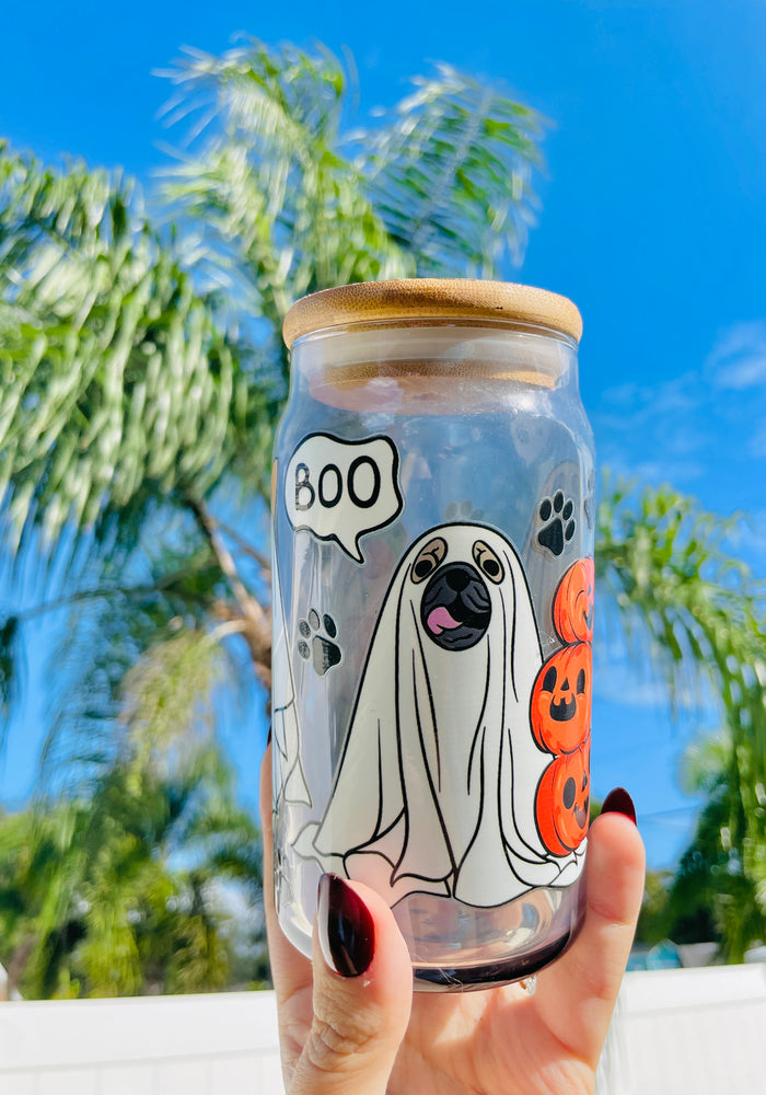 A 16 oz glass cup with a Halloween design of dogs dressed as ghosts, featuring “boo” speech bubbles, paw prints, a bamboo lid, and a reusable glass straw.
