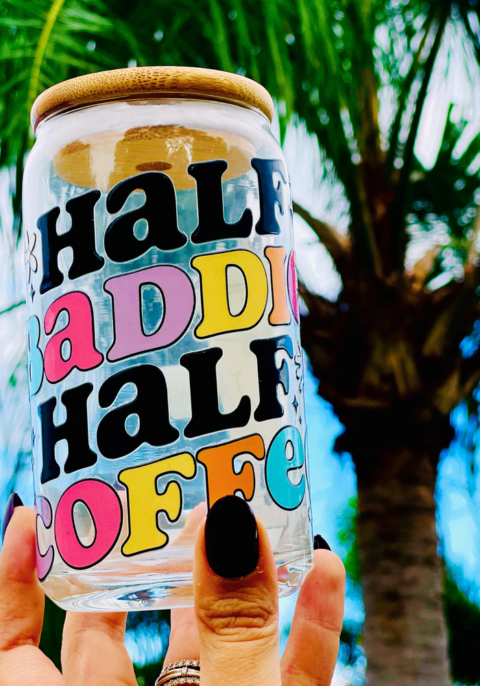 A 16 oz glass cup featuring a retro ‘Half Baddie Half Coffee’ design with bold lettering and a cute iced coffee character. Includes a bamboo lid and reusable glass straw, perfect for cold drinks. BPA-free and handwash only.
