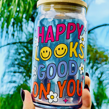 Load image into Gallery viewer, A 16oz BPA-free glass cup featuring a retro-inspired UVDTF design with smiley faces, daisies, and the phrase &quot;Happy Looks Good on You,&quot; complete with a bamboo lid and reusable glass straw.
