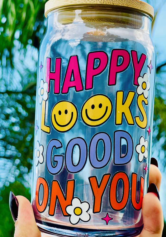 A 16oz BPA-free glass cup featuring a retro-inspired UVDTF design with smiley faces, daisies, and the phrase 