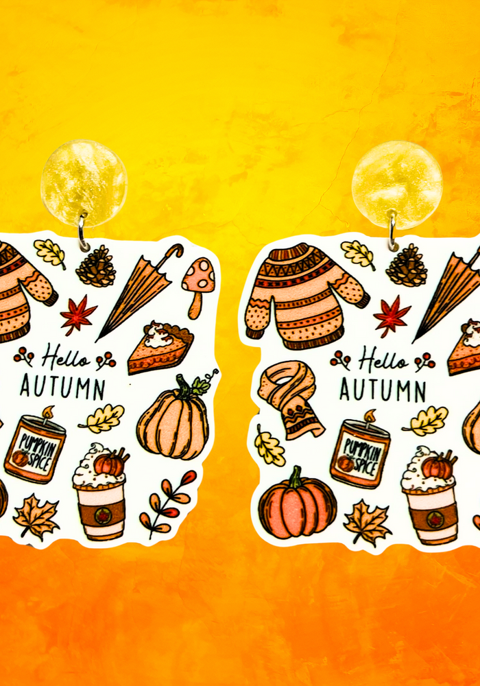 Orange background with earrings with the phrase 'Hello Autumn' featuring doodles of a scarf, sweater, pumpkin, leaves, coffee, candles, and pumpkin pie, perfect for cozy fall enthusiasts