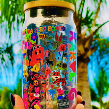 Load image into Gallery viewer, A 16 oz glass cup with a colorful Karol G-inspired UVDTF wrap featuring vibrant symbols, designs, and playful details. Includes a bamboo lid and reusable glass straw, perfect for cold drinks. BPA-free and handwash only.
