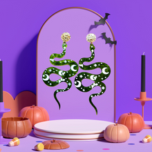 Load image into Gallery viewer, A purple earring stand with earrings featuring a mystic green snake on marbled acrylic with celestial markings, perfect for fans of unique Halloween accessories.
