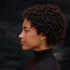 A model in front of a dark background wearing mystic green snake earrings with celestial markings, perfect for fans of unique Halloween accessories.